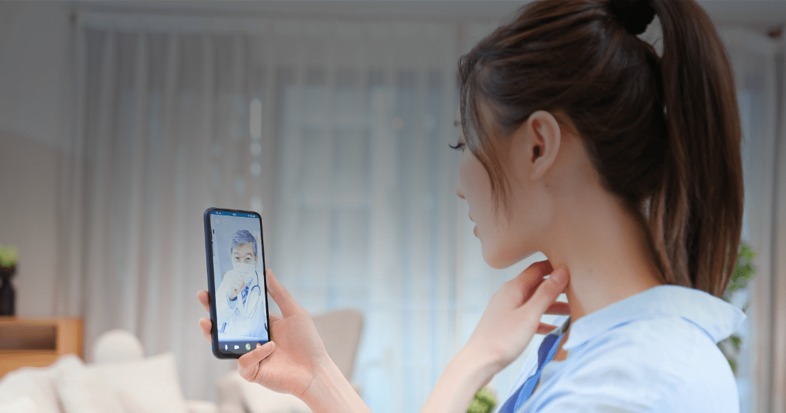 A woman looks at her phone, consulting with a doctor via a telehealth platform"